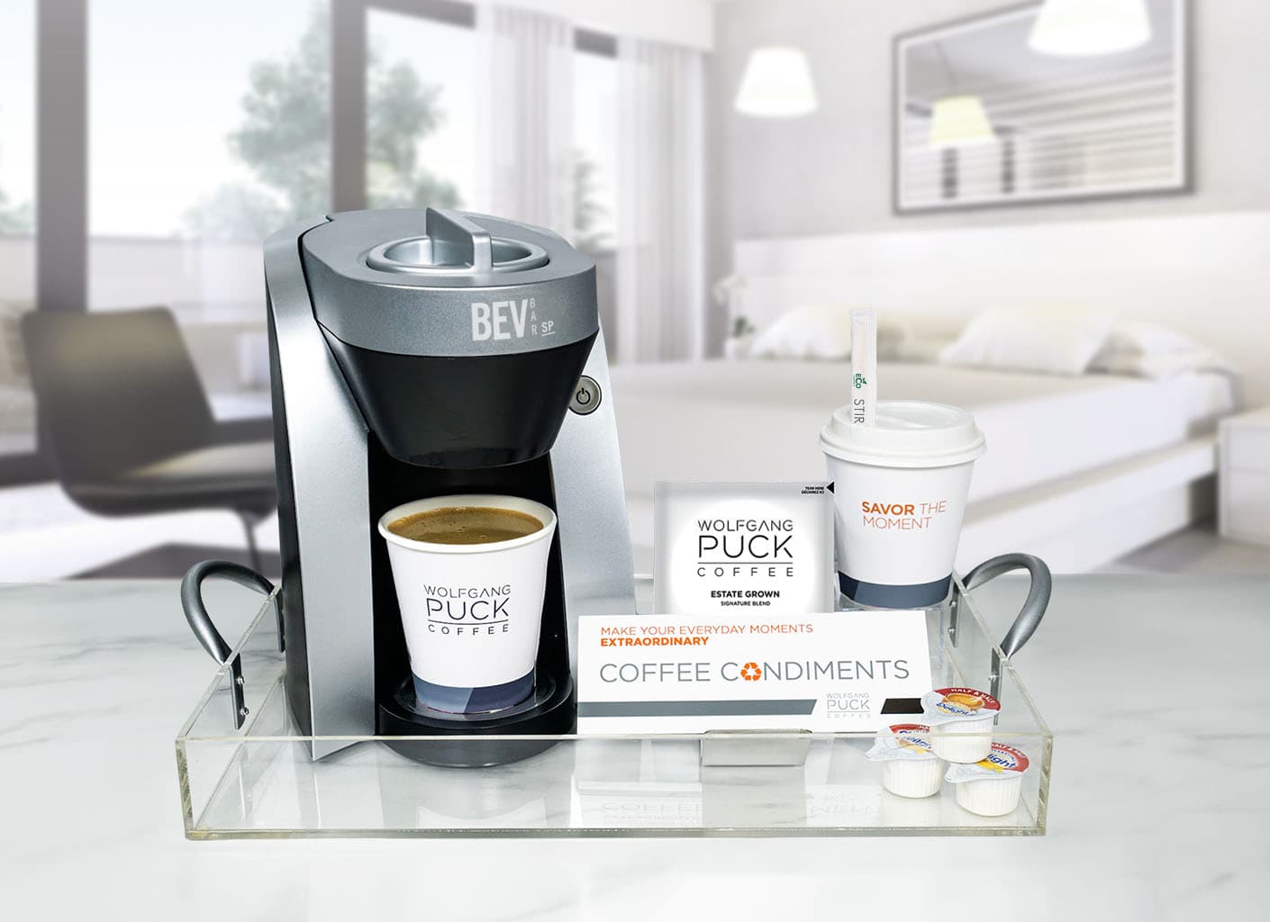 Wolfgang Puck BEV Bar single-serve coffee maker with Estate Grown filter pouch and coffee condiments on acrylic tray